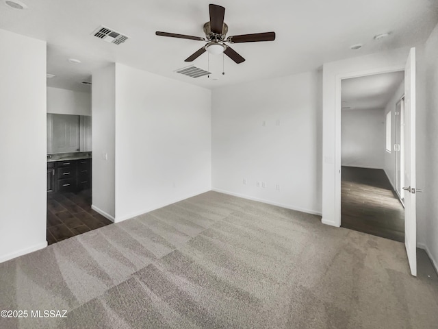 empty room with dark colored carpet and ceiling fan