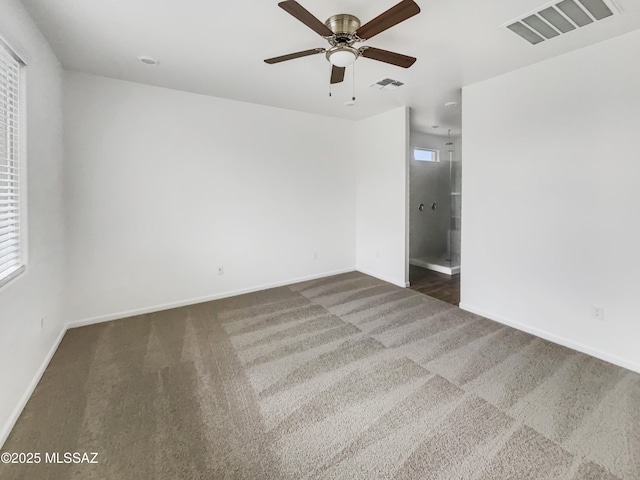 spare room with ceiling fan and dark carpet