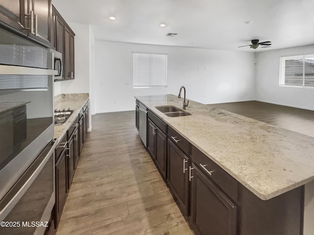 kitchen featuring sink, wood-type flooring, a center island with sink, appliances with stainless steel finishes, and ceiling fan