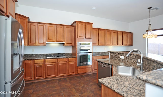 kitchen featuring sink, decorative light fixtures, stainless steel appliances, and dark stone counters