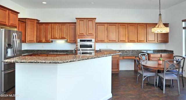 kitchen with pendant lighting, a kitchen island with sink, stainless steel appliances, and dark stone counters