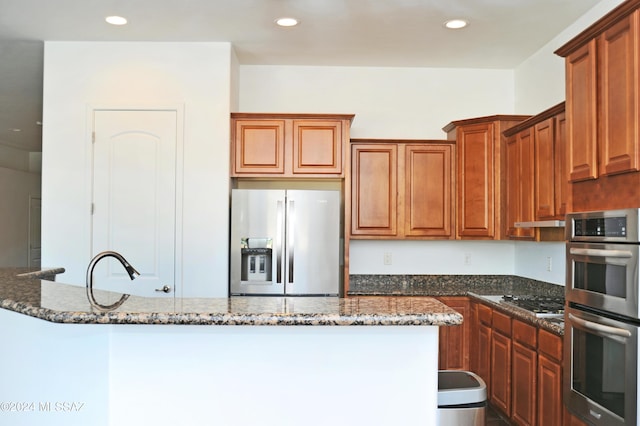 kitchen featuring stainless steel appliances, sink, and dark stone counters