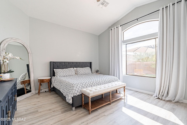 bedroom featuring light wood-type flooring, lofted ceiling, visible vents, and baseboards