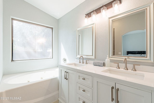 full bathroom featuring lofted ceiling, double vanity, a tub with jets, and a sink