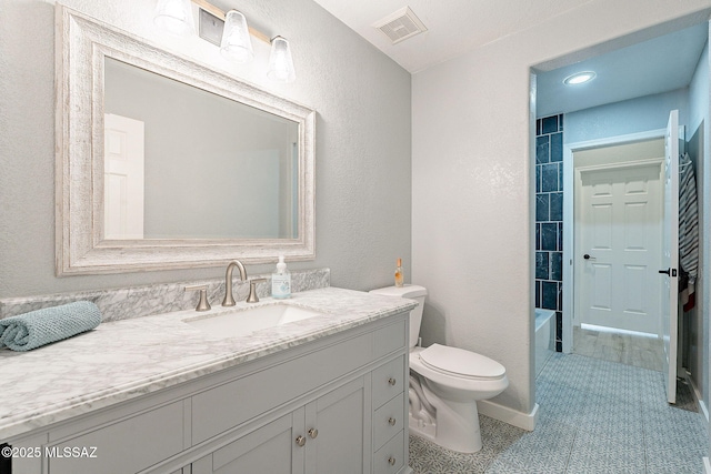 bathroom featuring visible vents, a textured wall, vanity, and toilet