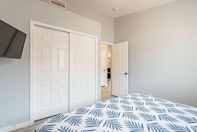 bedroom with light wood-style flooring, a closet, and visible vents