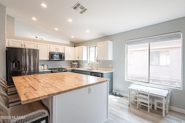 kitchen featuring visible vents, appliances with stainless steel finishes, a breakfast bar, light wood-type flooring, and white cabinetry