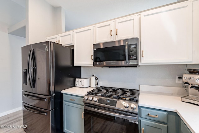 kitchen featuring stainless steel appliances, light countertops, light wood-style floors, and baseboards