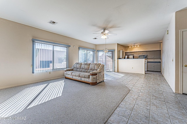 unfurnished living room with ceiling fan with notable chandelier and light tile patterned floors