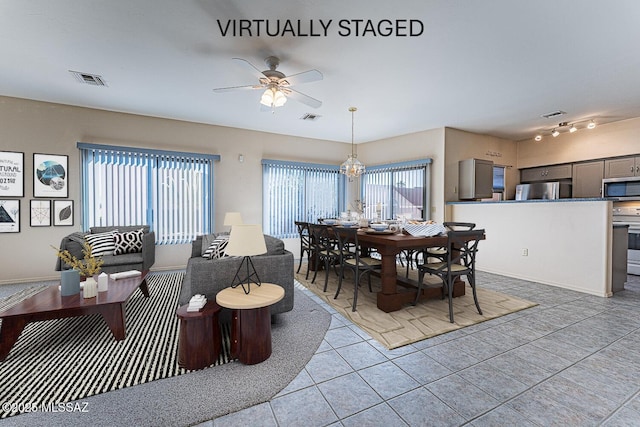 tiled dining room featuring ceiling fan with notable chandelier