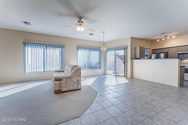 tiled living room with ceiling fan with notable chandelier