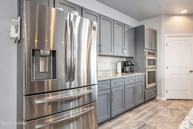 kitchen featuring gray cabinetry, light stone countertops, and stainless steel appliances