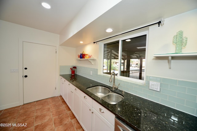 kitchen with sink, light tile patterned floors, dark stone countertops, white cabinets, and decorative backsplash