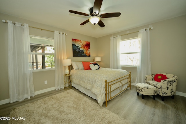 bedroom featuring multiple windows, wood-type flooring, and ceiling fan