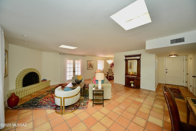 tiled living room with a fireplace, a skylight, and french doors