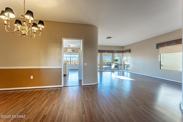 spare room with dark wood-type flooring and an inviting chandelier