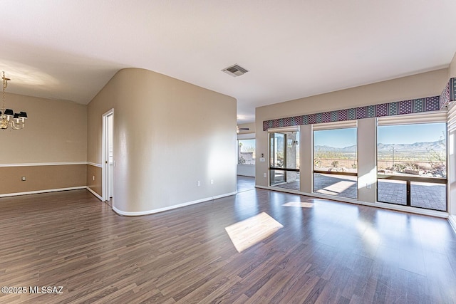 unfurnished room with an inviting chandelier and dark hardwood / wood-style floors