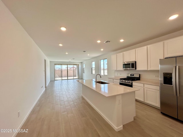 kitchen with white cabinets, stainless steel appliances, light wood finished floors, and visible vents
