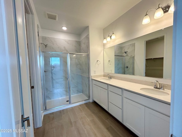 full bath featuring double vanity, a sink, a marble finish shower, and visible vents