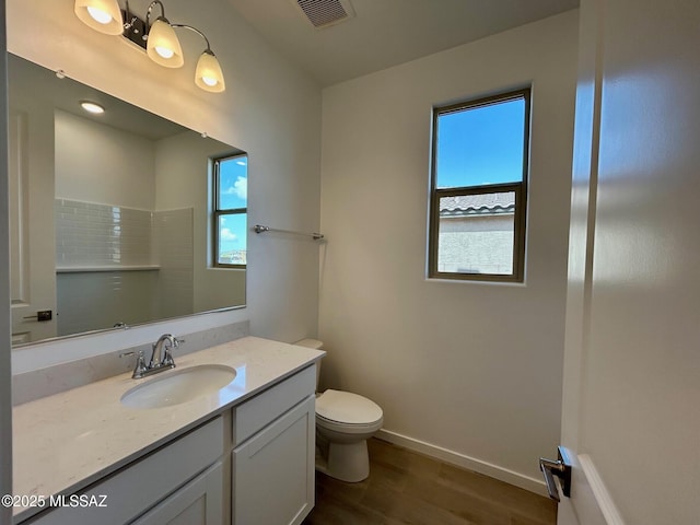 full bathroom with vanity, toilet, baseboards, visible vents, and wood finished floors