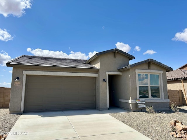 ranch-style home with fence, an attached garage, concrete driveway, a tile roof, and stucco siding