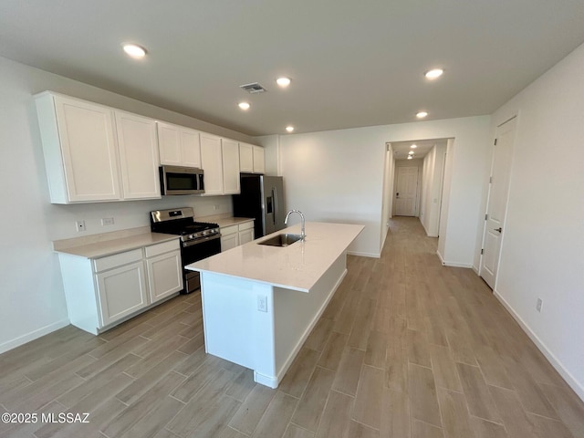 kitchen with a sink, wood tiled floor, visible vents, and stainless steel appliances
