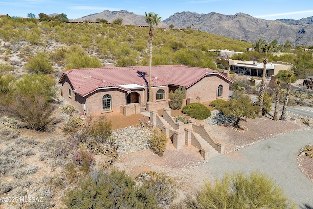 mediterranean / spanish-style home featuring stucco siding, a mountain view, and a tiled roof