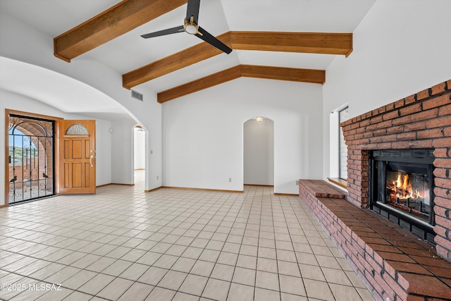 unfurnished living room with arched walkways, a brick fireplace, ceiling fan, and light tile patterned floors