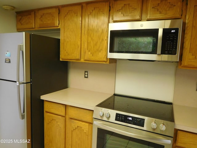 kitchen with brown cabinets, appliances with stainless steel finishes, and light countertops