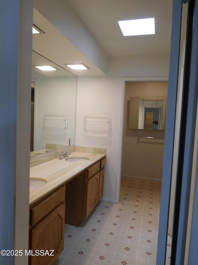full bath featuring tile patterned floors, double vanity, a sink, and baseboards