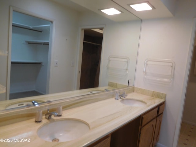 full bathroom featuring double vanity, a sink, and a walk in closet