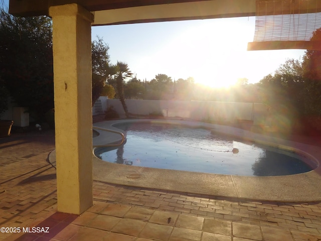 pool at dusk with a patio area