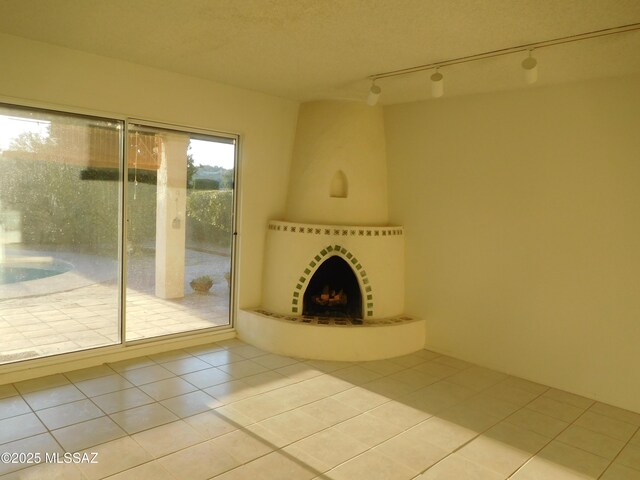 unfurnished living room featuring light tile patterned floors, a fireplace, and rail lighting