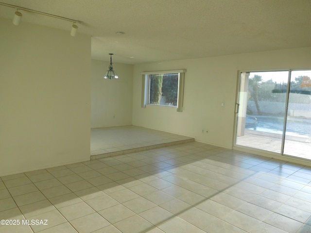 7932 N Casas Cameo, Tucson, AZ 85742 - empty room with healthy amount of natural light, light tile patterned flooring, and track lighting