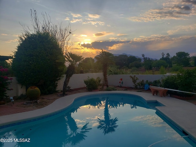 pool at dusk featuring a fenced backyard and a fenced in pool