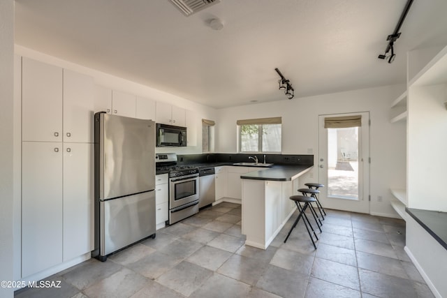 kitchen with kitchen peninsula, stainless steel appliances, sink, white cabinets, and a kitchen breakfast bar