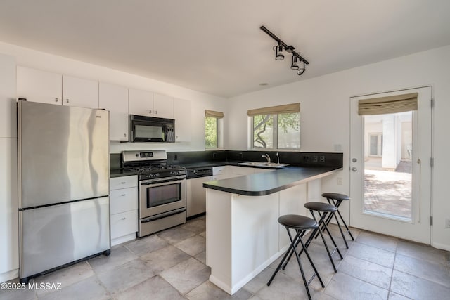 kitchen featuring sink, a breakfast bar, stainless steel appliances, kitchen peninsula, and white cabinets