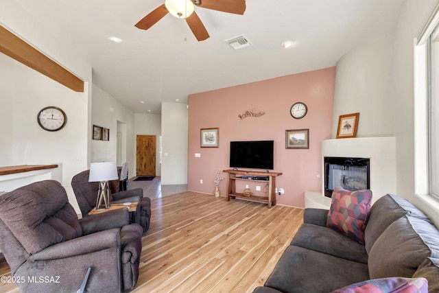 living room with ceiling fan, a fireplace, and light hardwood / wood-style floors