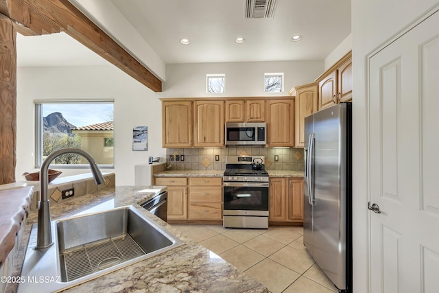 kitchen with light tile patterned flooring, sink, stainless steel appliances, light stone countertops, and decorative backsplash