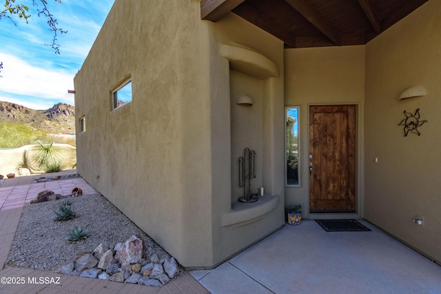 view of exterior entry with a patio and a mountain view