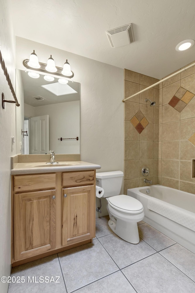 full bathroom featuring vanity, tiled shower / bath combo, tile patterned floors, and toilet