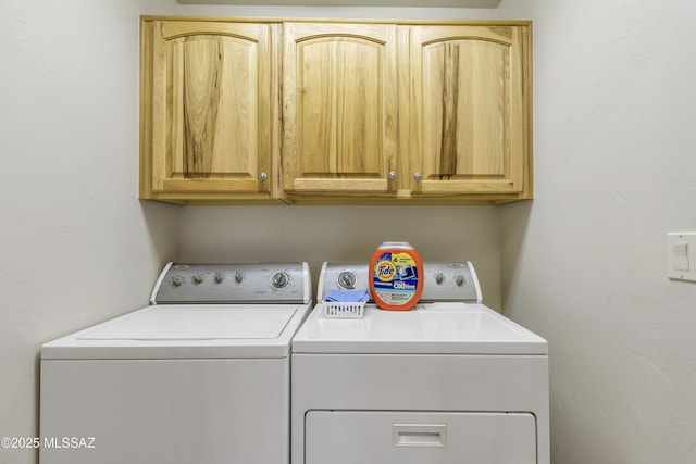 clothes washing area with cabinets and washer and clothes dryer