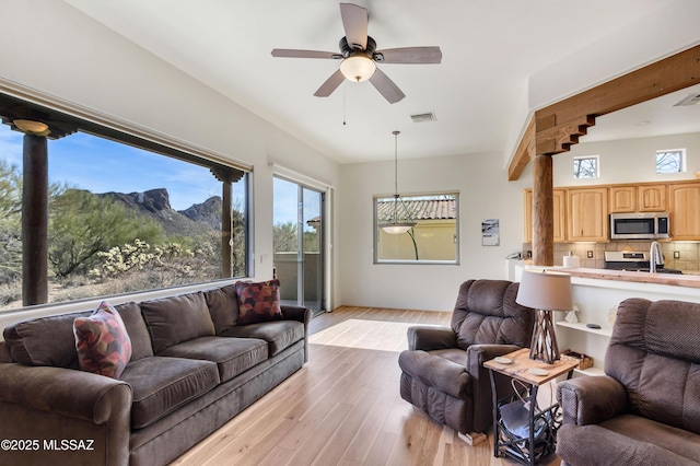 living room with ceiling fan, a mountain view, sink, and light wood-type flooring