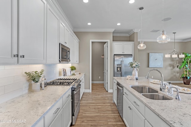 kitchen with sink, appliances with stainless steel finishes, hanging light fixtures, light stone counters, and white cabinets