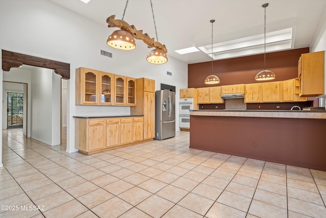 kitchen with tasteful backsplash, stainless steel fridge with ice dispenser, a towering ceiling, and light brown cabinets