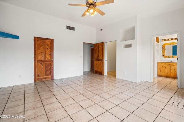 unfurnished bedroom featuring light tile patterned flooring, connected bathroom, and ceiling fan