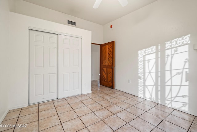 unfurnished bedroom featuring ceiling fan, a closet, and light tile patterned floors