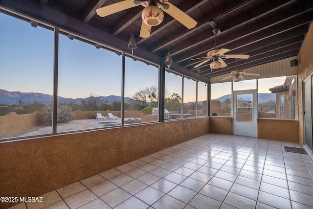 unfurnished sunroom featuring beamed ceiling, a mountain view, wooden ceiling, and ceiling fan