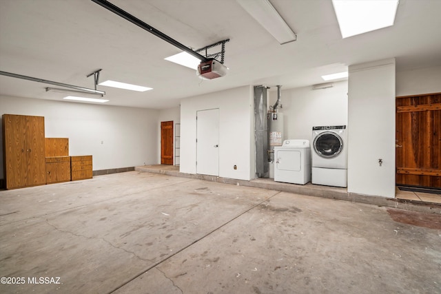 garage featuring a garage door opener, gas water heater, and separate washer and dryer