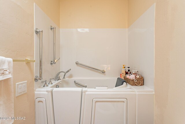 bathroom featuring a garden tub and washer / dryer